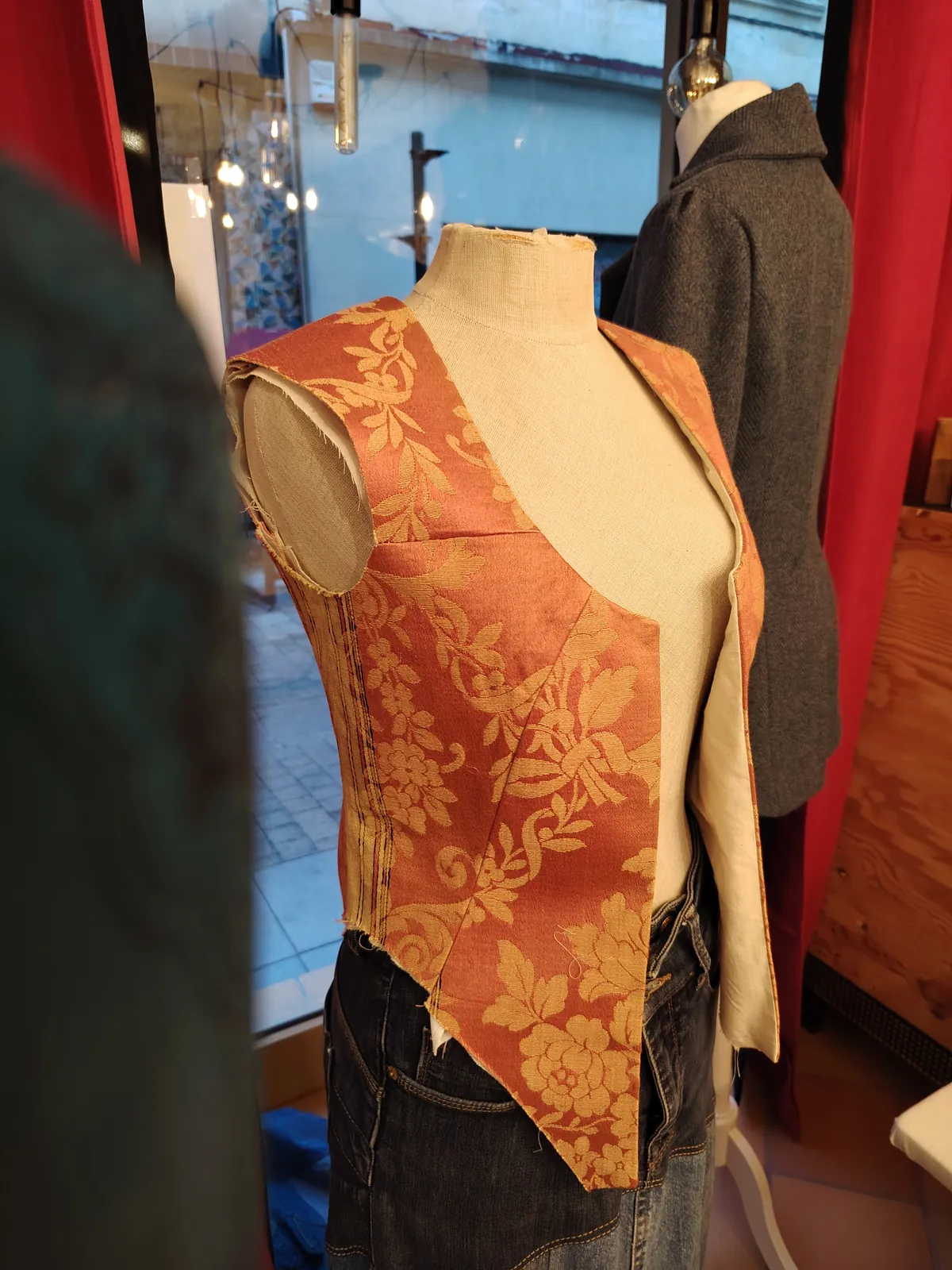 Bustier asymétrique en soie orange à motifs, drapé sur un mannequin de couture.