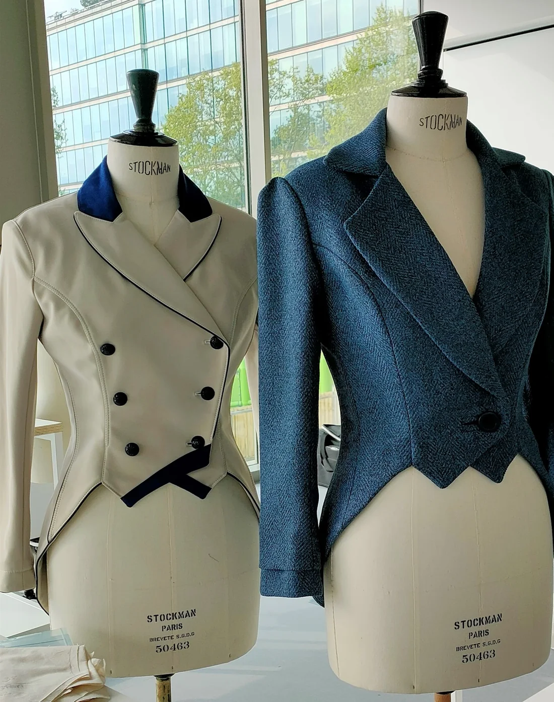 Deux vestes tailleur, l'une écrue croisée, l'autre bleue cintrée, présentées sur des mannequins Stockman.